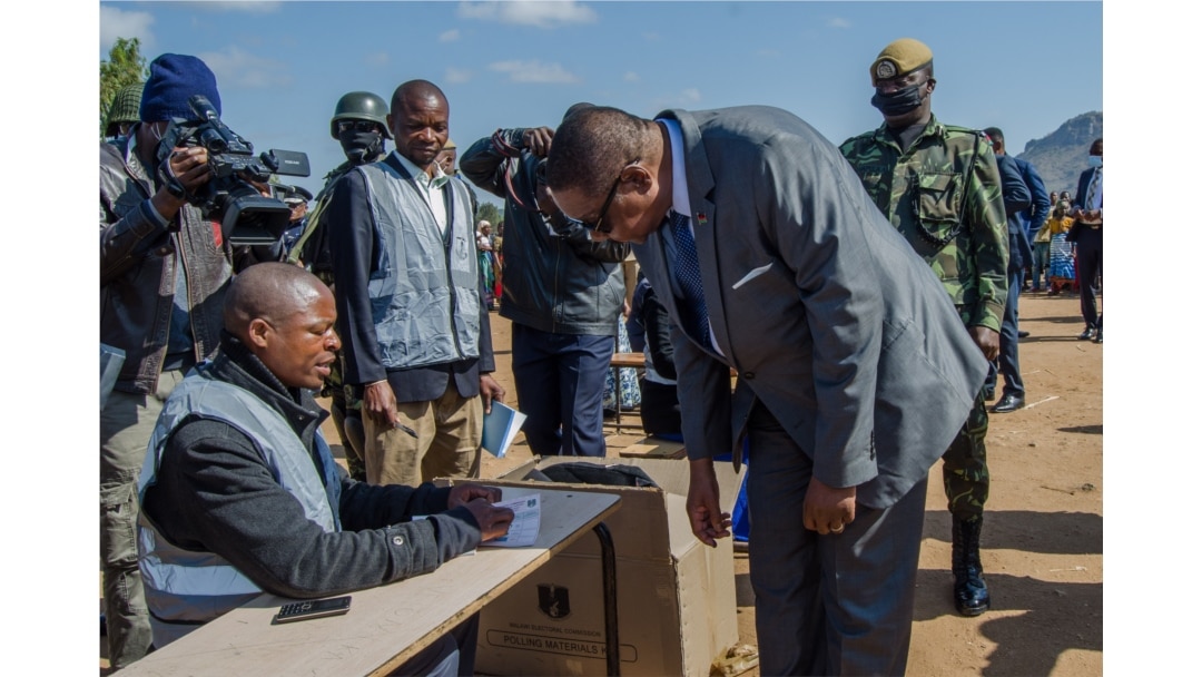 FILE - President Peter Mutharika gets instructions on how to vote from a presidisng officer, in Thyolo district. (Lameck Masina/VOA)