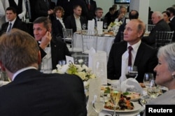 FILE - Russian President Vladimir Putin, right, sits next to retired U.S. Army Lieutenant General Michael Flynn, left, at an exhibition marking the 10th anniversary of the RT (Russia Today) television news channel in Moscow, Dec.10, 2015.
