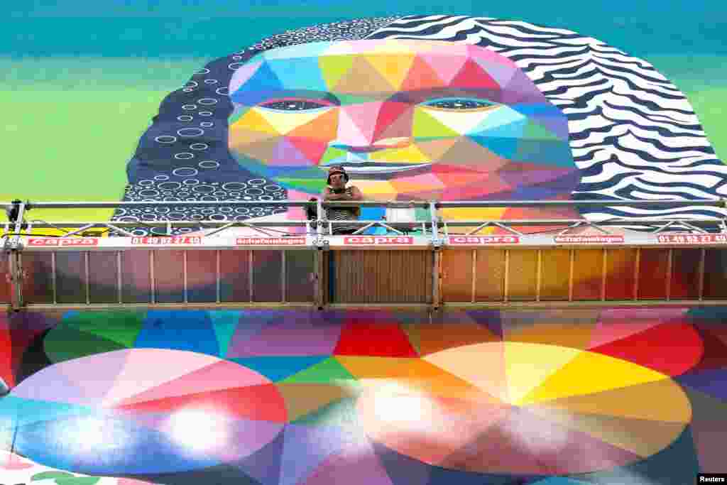 Spanish artist Okuda poses in front of his 50-meter-high wall mural representing his interpretation of the famous Mona Lisa painting, in Paris, France.