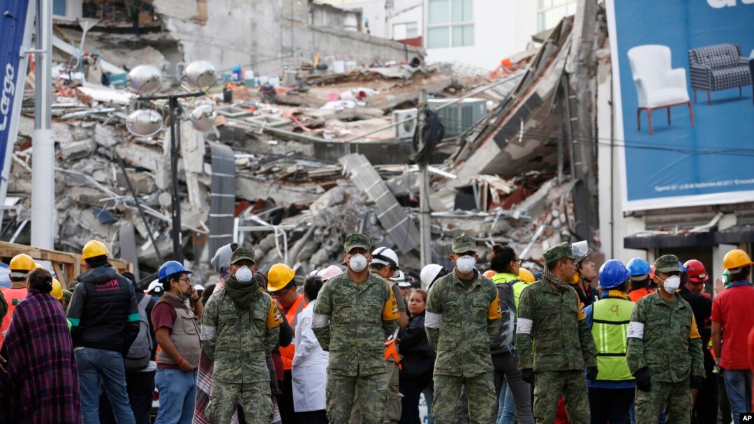 Rescue workers and volunteers stand in the middle of the street after an earthquake alarm sounded and a small tremor was felt during rescue operations at the site of a collapsed building in Roma Norte, in Mexico City, Saturday, Sept. 23, 2017. 