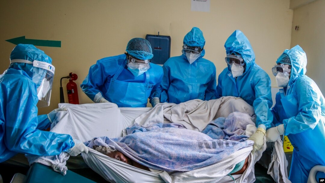 FILE - In this April 14, 2021, photo, a medical team rolls a coronavirus patient from a bed onto a stretcher in the COVID-19 intensive care unit at Kenyatta National Hospital, in Nairobi, Kenya.