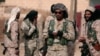 FILE - A Syrian Democratic Forces (SDF) fighter uses a mobile phone as he stands with fellow fighters in the town of Hisha, Syria, after they took control of the area from Islamic State militants, Nov. 14, 2016. The Pentagon sees the SDF as an effective fighting force against IS militants. 