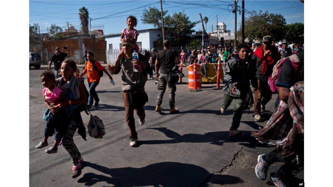 Migrants run toward the U.S. after breaking past a line of Mexican police at the Chaparral border crossing in Tijuana, Mexico, Nov. 25, 2018, near the San Ysidro, California, entry point.