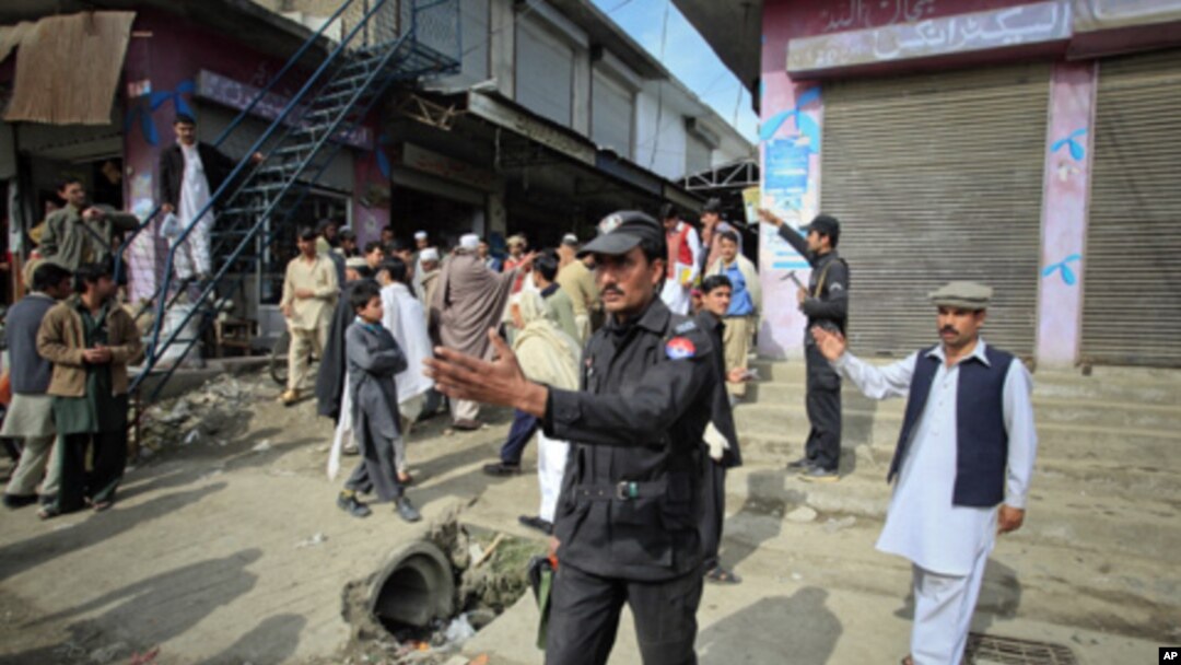 Policemen ask residents to disperse as they stand near the site of a deadly suicide bomb attack at a paramilitary training center in Mardan, northwest Pakistan, February 10, 2011.