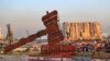 A justice symbol monument is seen in front of towering grain silos that were gutted in the massive Aug. 2020 explosion at the port that claimed the lives of more than 200 people, in Beirut, Lebanon, Aug. 4, 2021. 