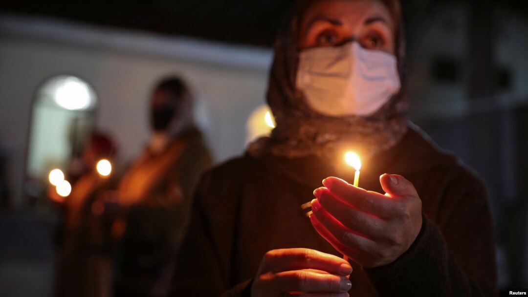 A believer wearing a protective mask holds a candle outside a church during an Orthodox Easter service, amid the coronavirus disease outbreak, in Marneuli, Georgia, April 18, 2020. 