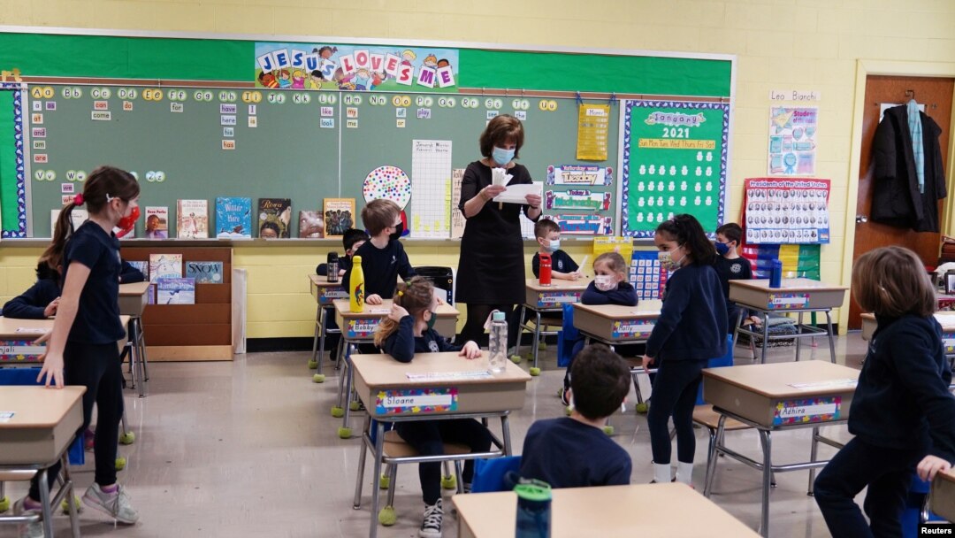 FILE - A teacher calls names for schoolchildren to collect a swab and test themselves for COVID-19 to prevent the spread of the coronavirus disease (COVID-19) in the classroom at South Boston Catholic Academy in Boston, Massachusetts, Jan. 28, 2021. 