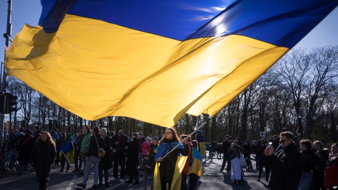 FILE - A woman waves a giant Ukrainian flag during a protest to mark two years since Russia's full-scale invasion on Ukraine, at the Brandenburg Gate, in Berlin, Saturday, Feb. 24, 2024. 