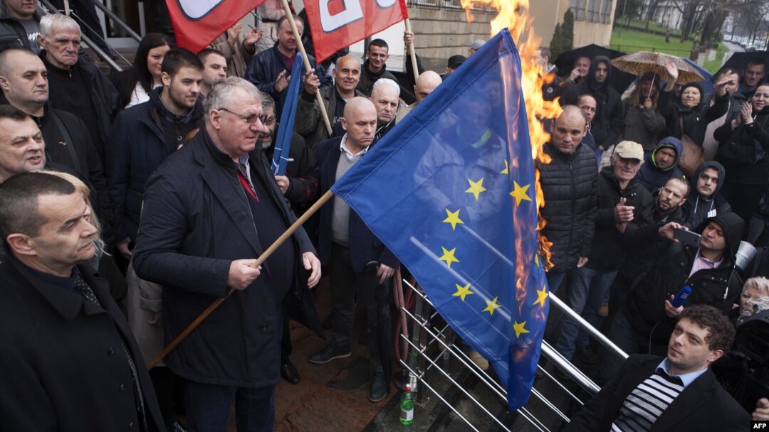 Serb ultranationalist leader Vojislav Seselj holds a burning European Union flag in front of the High Court building in Belgrade, March 10, 2016.