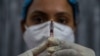 A health worker checks a syringe before performing a trial run of a COVID-19 vaccine delivery system, as India prepares to kick off the coronavirus vaccination drive, in Gauhati, India, Jan. 8, 2021. 
