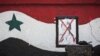Damaged portrait of former Syrian President Hafez Assad at the entrance of a military academy besieged by rebels, Aleppo, Dec. 16, 2012.