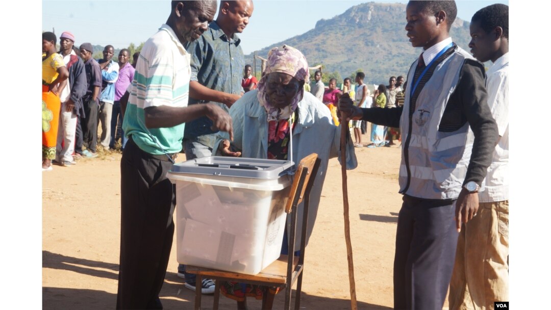 Polling monitors offer assistance as an elderly woman casts her vote in Tuesday's election in Malawi. (L Masina/VOA)