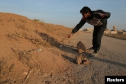 FILE - A resident points to what he believes is a landmine in the village of al-Heesha in Raqqa district of Syria after it was captured from Islamic State, Nov. 15, 2016.