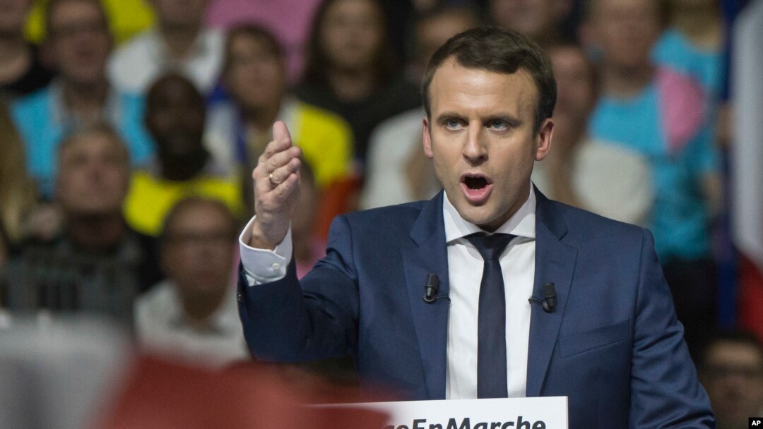 FILE - Supporters of French presidential candidate Emmanuel Macron hold placards as he speaks during a campagin rally in Lyon, central France, Feb. 4, 2017.