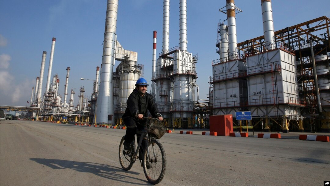 FILE - Iranian oil worker rides his bicycle at the Tehran's oil refinery south of the capital Tehran, Iran.