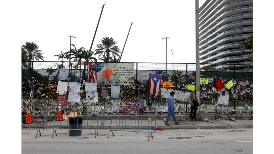 A man walks past a memorial site created by neighbors as search and rescue efforts resume the day after the managed demolition of the remaining part of Champlain Towers South complex in Surfside, Florida, July 5, 2021.