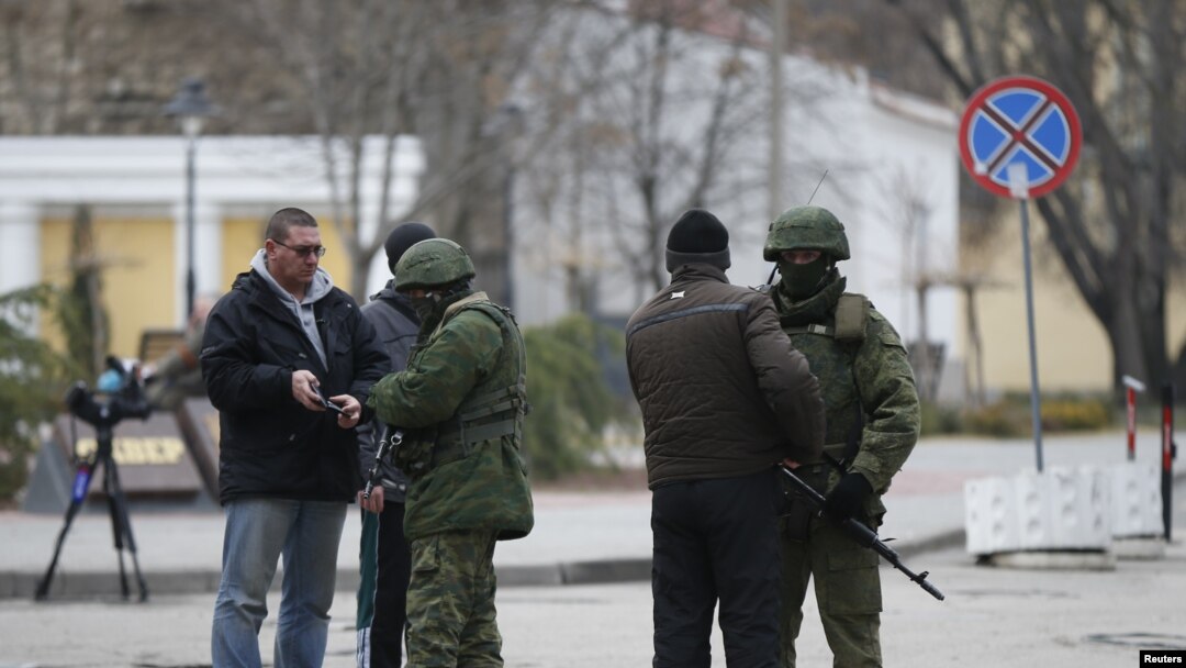 Armed men check journalists documents around the regional parliament building in the Crimean city of Simferopol March 1, 2014.