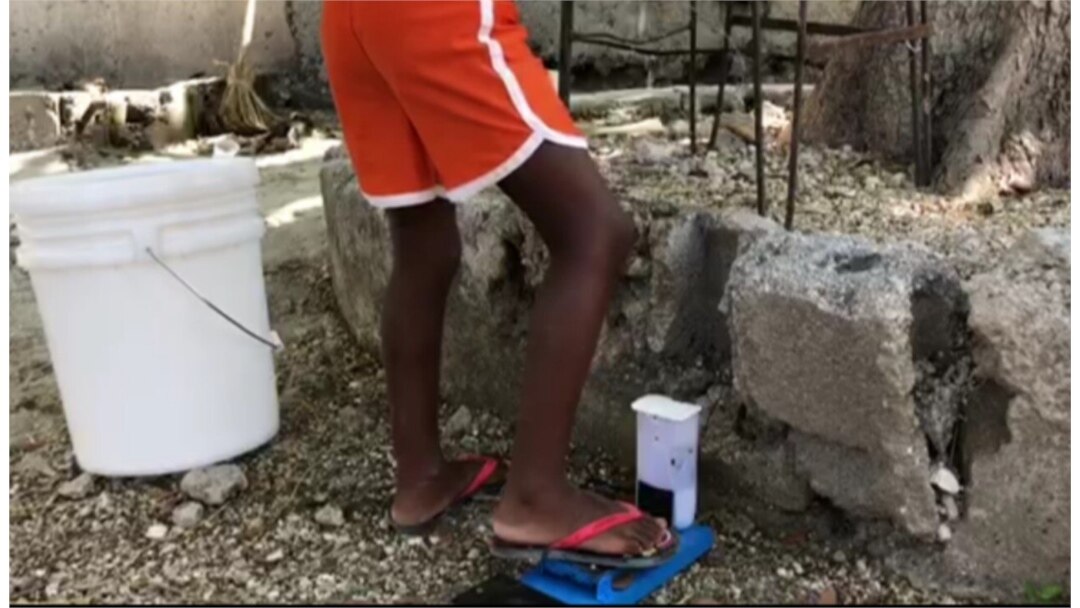 When a person steps on the pedal, the bucket releases water. (Photo: Matiado Vilme / VOA)