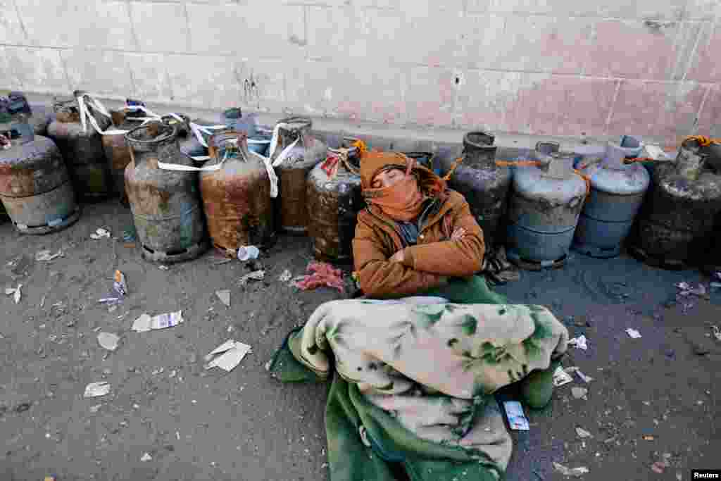 A man sleeps next to a queue of cooking gas cylinders outside a gas filling station amid a scarcity in cooking gas supplies in Sana&#39;a, Yemen.