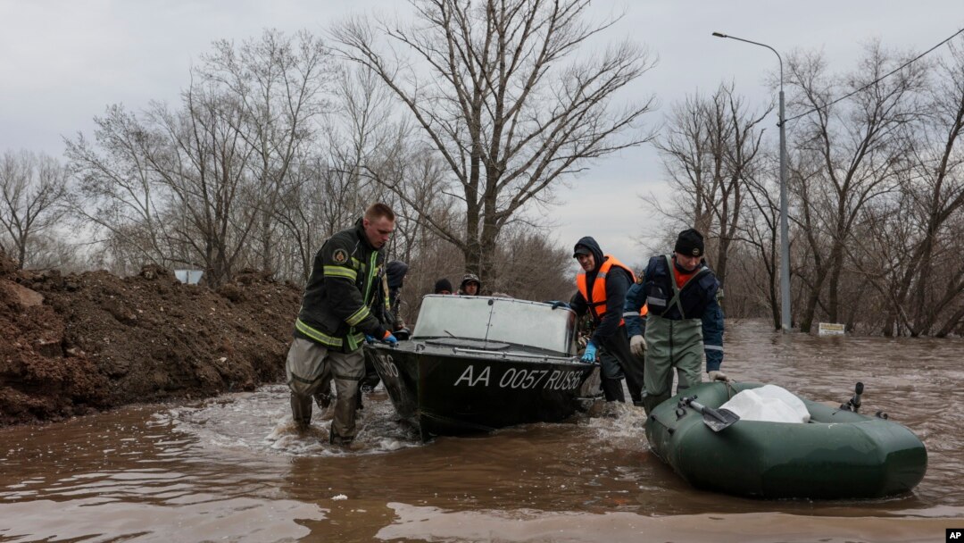 Emergency workers push their boats in a flooded area in Orenburg, Russia, Wednesday, April 10, 2024. Russian officials are scrambling to help homeowners displaced by floods, as water levels have risen in the Ural River. 