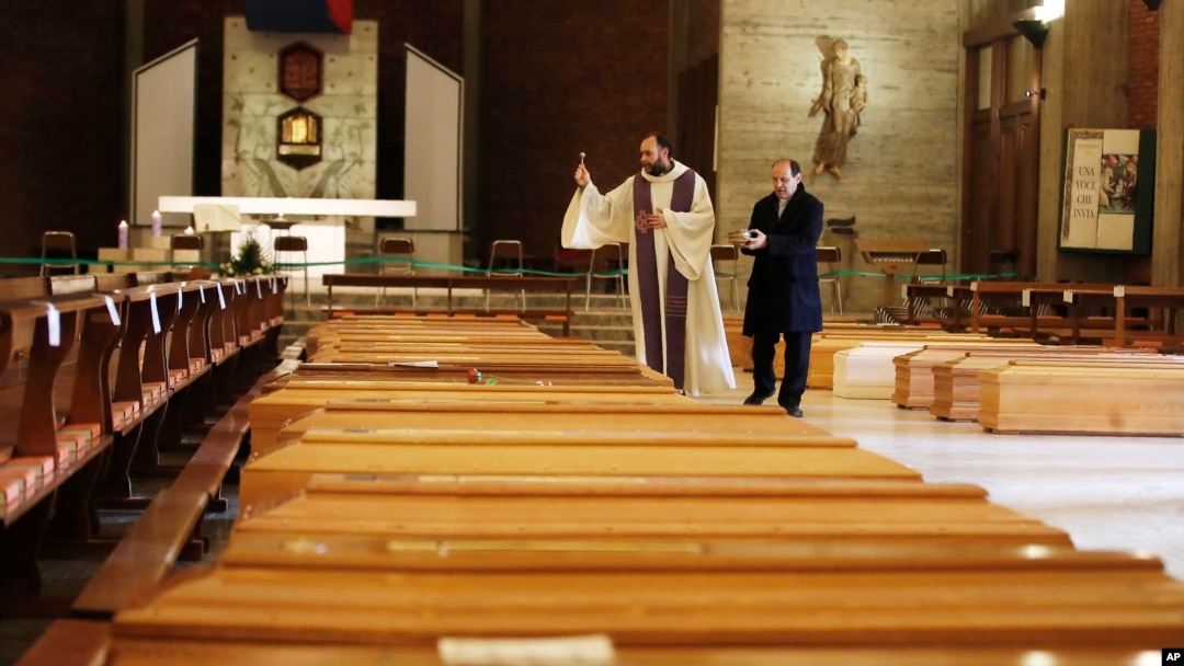 Don Marcello Crotti, left, blesses the coffins with Don Mario Carminati in the San Giuseppe church in Seriate, Italy, Saturday, March 28, 2020. The new coronavirus causes mild or moderate symptoms for most people, but for some, especially older…