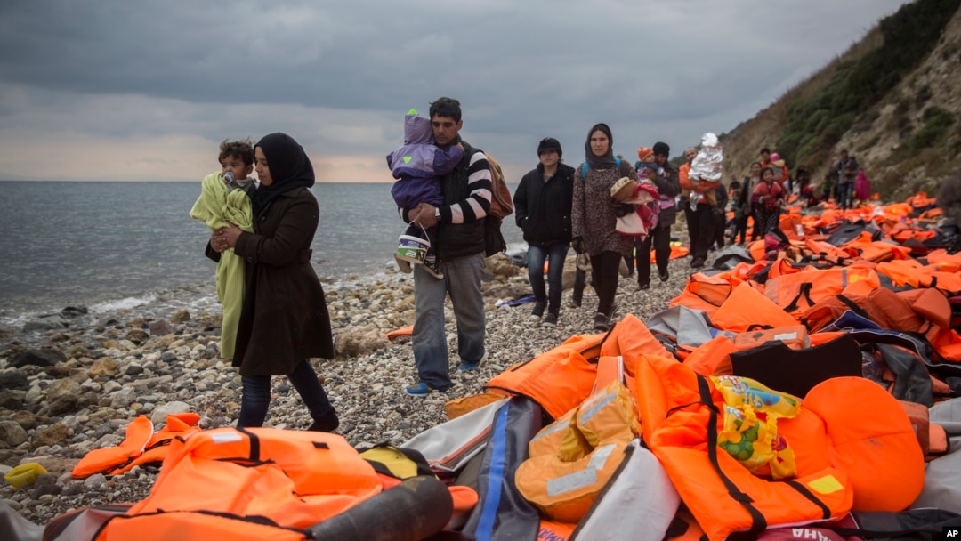 Refugees and migrants walk along a beach after crossing a part of the Aegean on a dinghy, from Turkey to the Greek island of Lesbos, Dec. 12, 2015. 