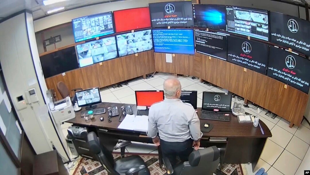In this undated frame grab taken from video shared with AP by a self-identified hacker group called 'The Justice of Ali,' a guard looks at surveillance screens taken over by the group, at Evin prison in Tehran. (The Justice for Ali via AP)