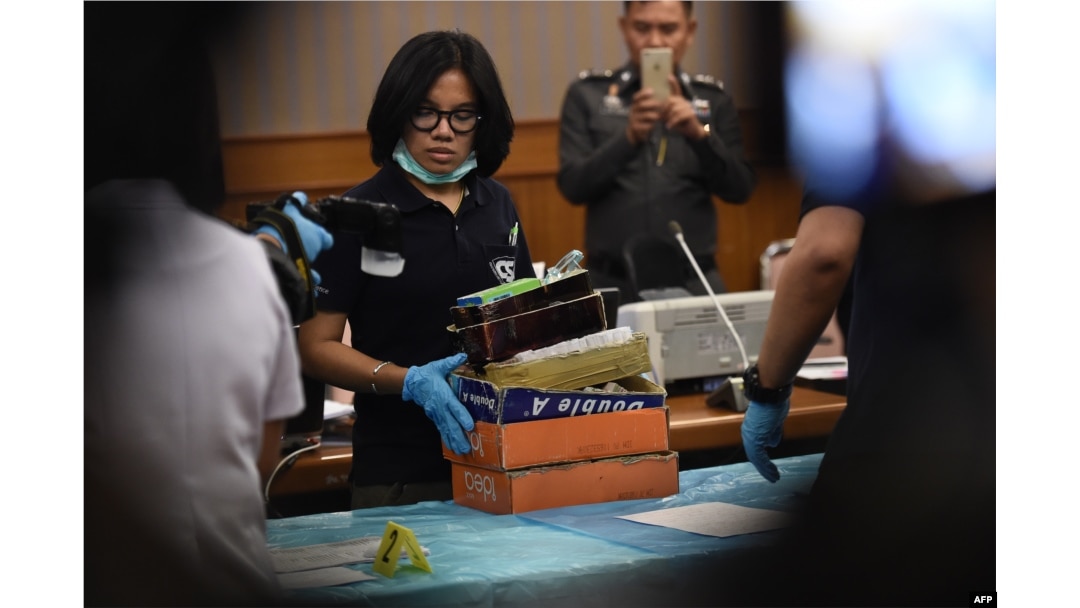 FILE - An employee from the Department of Special Investigation sorts through evidence from a massage parlor after police raided the premises because of suspicions of underage trafficking and prostitution, in Bangkok, Jan. 15, 2018.