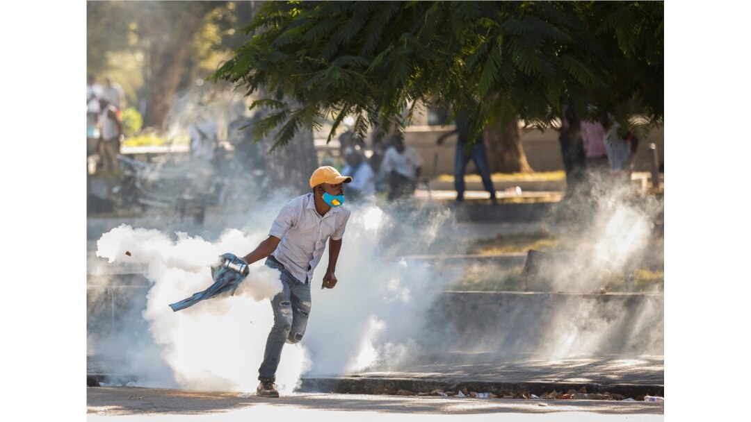 A demonstrator picks up a tear gas canister during protests against Haiti's President Jovenel Moise, in Port-au-Prince, Haiti, Feb. 8, 2021.