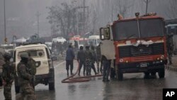 Indian firemen spray water on a road to wash away blood after an explosion in Pampore, Indian-controlled Kashmir, Thursday, Feb. 14, 2019. 