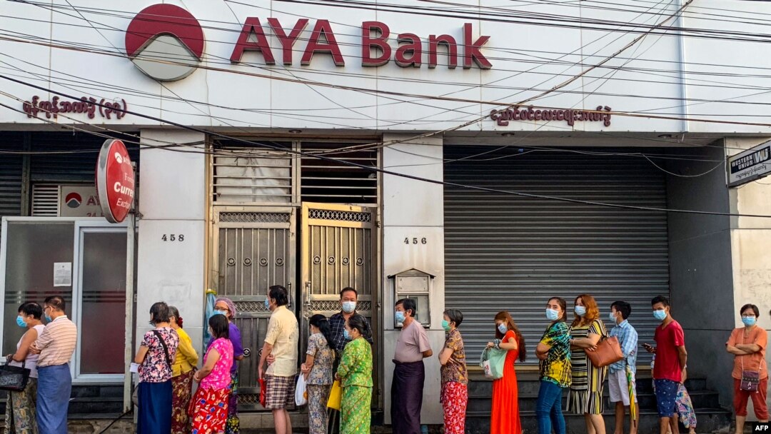 People wait for a branch of the AYA Bank to open, ahead of a long holiday stretch for the Myanmar New Year, also known as Thingyan, in Yangon on April 12, 2021, as the country remains in turmoil after the February military coup. (Photo by STR / AFP)