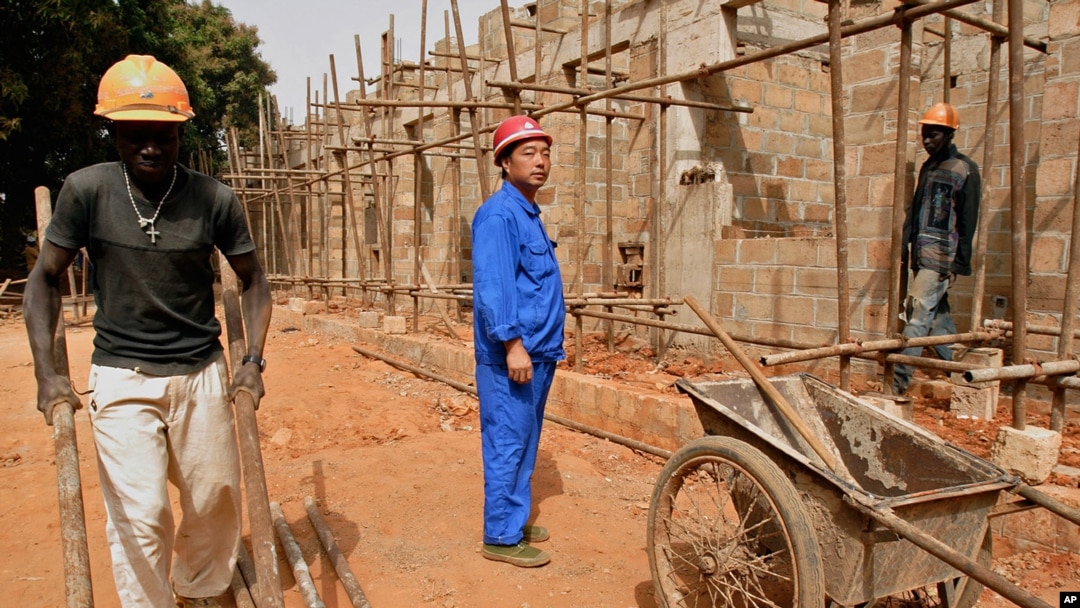 FILE - A Chinese foreman looks on as laborers work on the construction of military officers housing, donated by China, in Bissau, Guinea-Bissau, Jan. 3, 2007. 