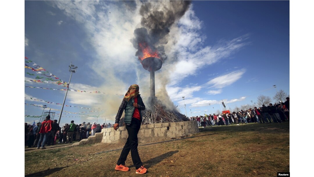 A masked demonstrator walks around a bonfire during a gathering to celebrate the spring festival of Newroz in the Kurdish-dominated southeastern city of Diyarbakir, Turkey, March 21, 2016.