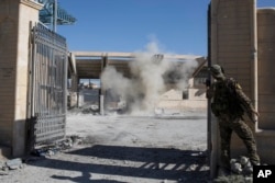 FILE - A member of the U.S.-backed Syrian Democratic Forces throws a bomb to check for more explosives at the stadium that was the site of Islamic State fighters' last stand in the city of Raqqa, Syria, Oct. 18, 2017.