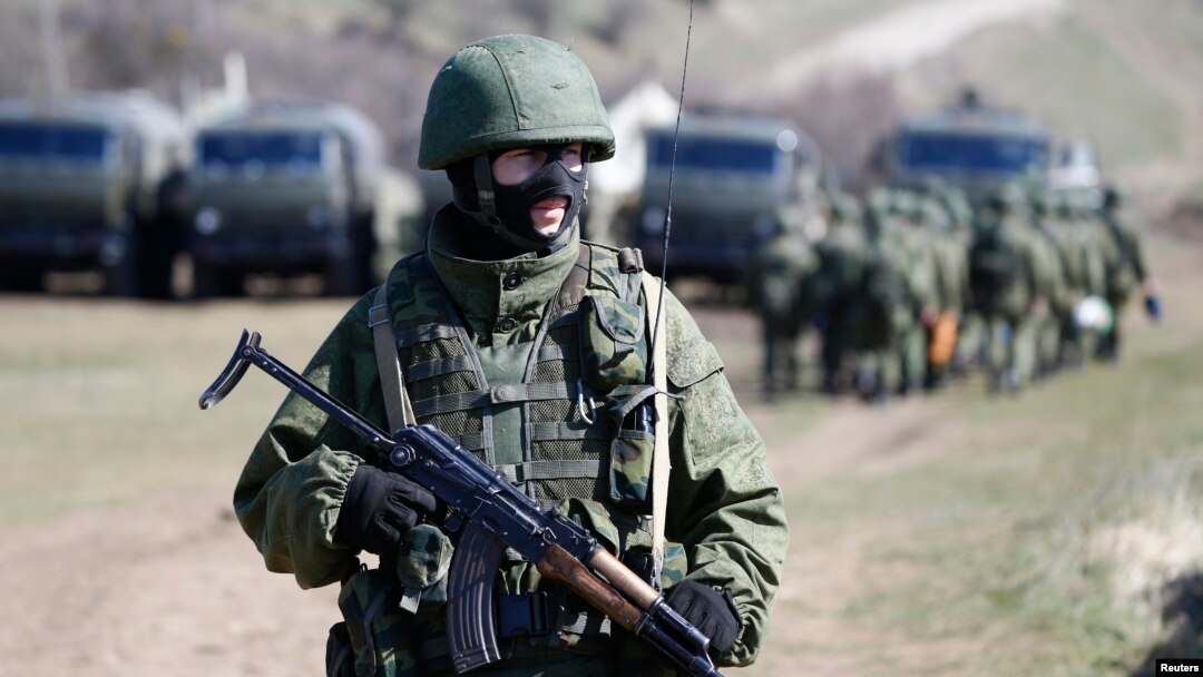 FILE - An armed man, believed to be a Russian soldier, stands guard outside a military base in Perevalne, near the Crimean city of Simferopol, March 21, 2014, during the days of Russia's annexation of Ukraine's Black Sea peninsula.