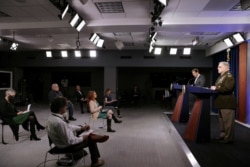 FILE - Members of the news media observe 'social distancing' as U.S. Defense Secretary Mark Esper and Joint Chiefs Chairman Army Gen. Mark Milley hold a news conference at the Pentagon in Arlington, Virginia, April 14, 2020.