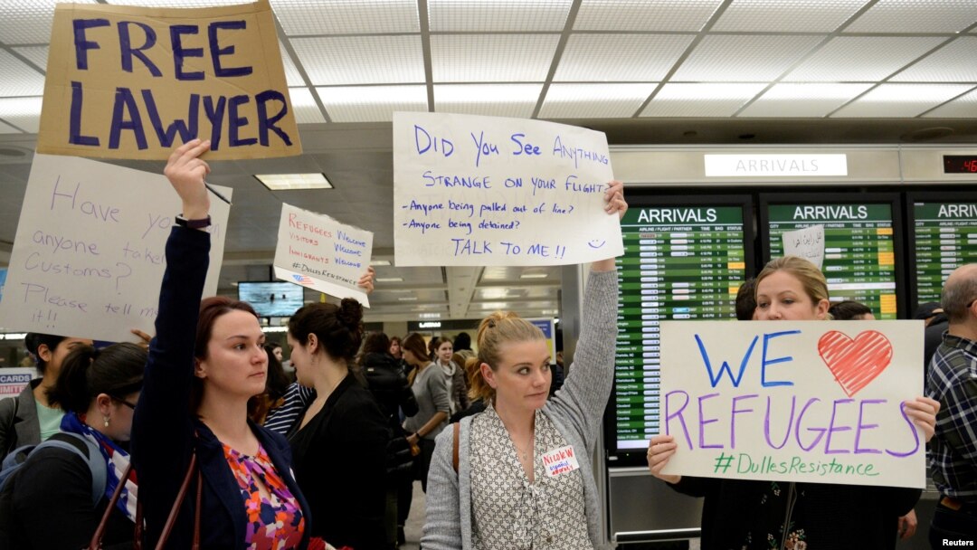 Lawyers offer free counseling as they join dozens of pro-immigration demonstrators cheering and holding signs as international passengers arrive at Dulles International Airport to protest President Donald Trump's travel ban in suburban Washington, Jan. 29
