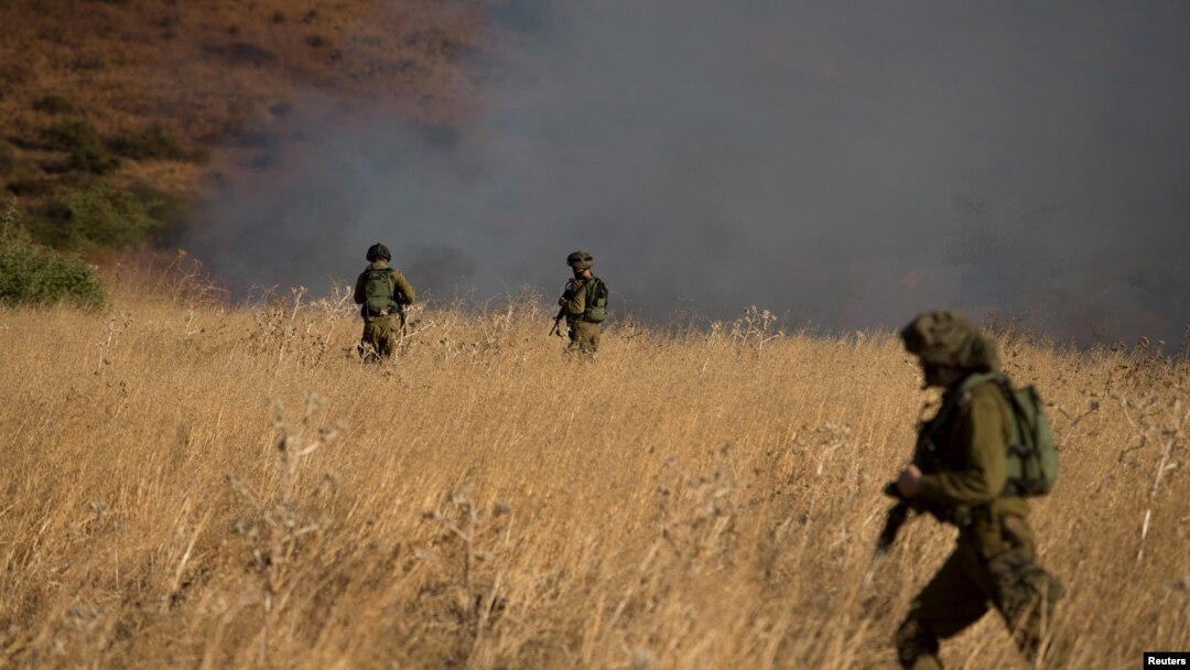 Israeli soldiers patrol next to a smoke from a fire caused by a rocket attack in northern Israel, near the Lebanese border, Aug. 20, 2015. 