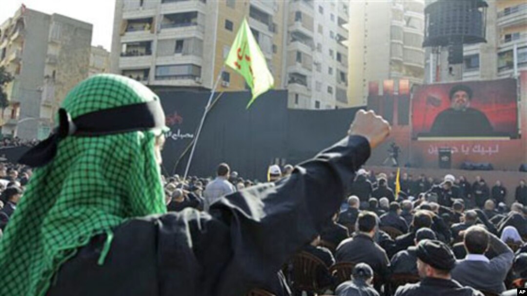 Lebanese Hezbollah supporters, raise their fists as they listen to Hezbollah's leader Sheik Hassan Nasrallah speak, on a giant screen, during Ashura day, in the suburbs of Beirut, 16 Dec 2010