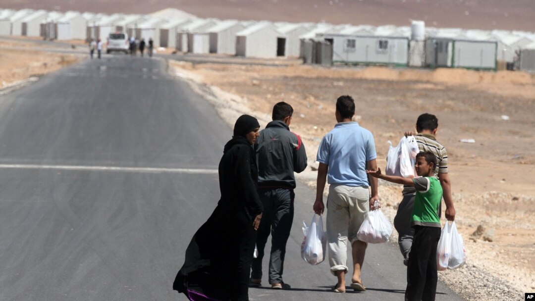 A Syrian refugee family walks towards the new Syrian camp of Azraq, which stretches for 15 kilometers, and lies about 100 kilometers from the Syrian border in Jordan, Wednesday, April 30, 2014.