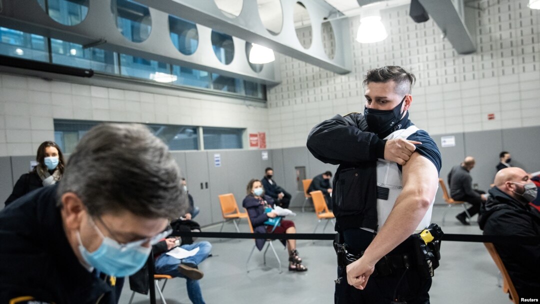 FILE - A member of the New York Police Department rolls up his sleeve before receiving a dose of the Moderna COVID-19 vaccination at Queens Police Academy in the Queens borough of New York, Jan. 11, 2021. 