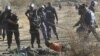 South African policemen give instructions to an injured miner after striking miners were shot outside a South African mine in Rustenburg, 100 km northwest of Johannesburg on August 16, 2012. 