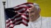 FILE - The U.S. flag flies in front of a mural of Pope Francis on the side of a building in midtown Manhattan in New York, Aug. 28, 2015.