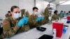 FILE - U.S. Army health specialists fill syringes with the Pfizer COVID-19 vaccine, in Miami, Florida, March 9, 2021.