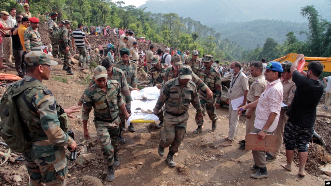Army soldiers and rescue workers recover bodies of landslide victims even as they try to pull out two buses that were covered in mud after a landslide in Urla village, Himachal Pradesh state, India, Aug. 13, 2017. 
