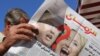 An Iraqi man holds an edition of Iraqi daily newspaper Azzaman displaying pictures of US presidential candidates Donald Trump and Hillary Clinton in Baghdad, Nov. 9, 2016. 
