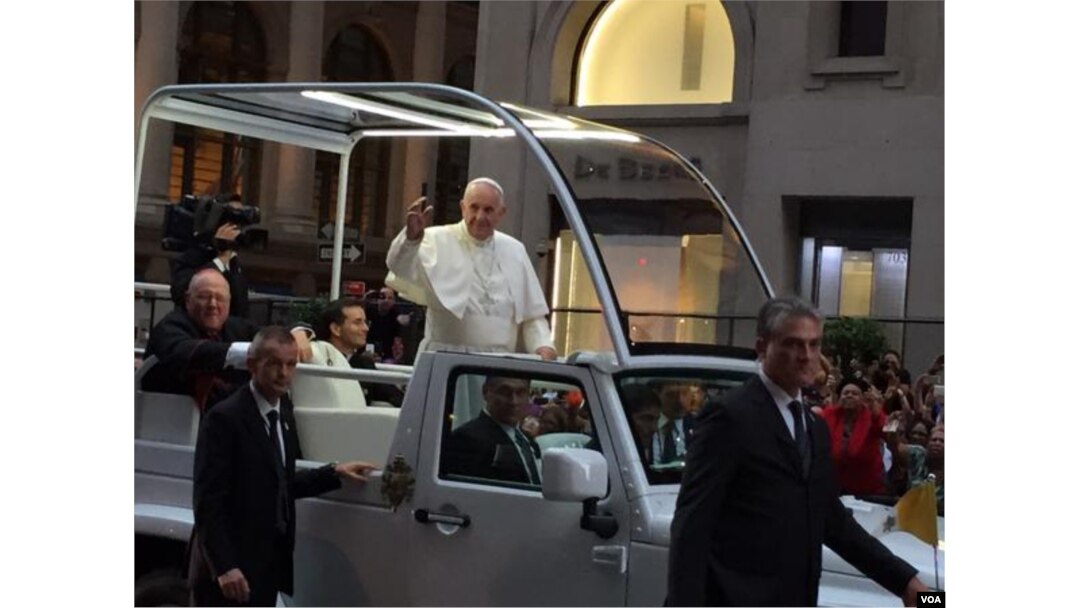 Pope Francis waves to huge crowds gathered in Manhattan as his motorcade drives along Fifth Avenue in New York, Sept. 24, 2015. (C. Presutti / VOA)
