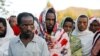 FILE - Men stand in line to receive food donations, at the Tsehaye primary school, which was turned into a temporary shelter for people displaced by conflict, in the town of Shire, Tigray region, Ethiopia, March 15, 2021.