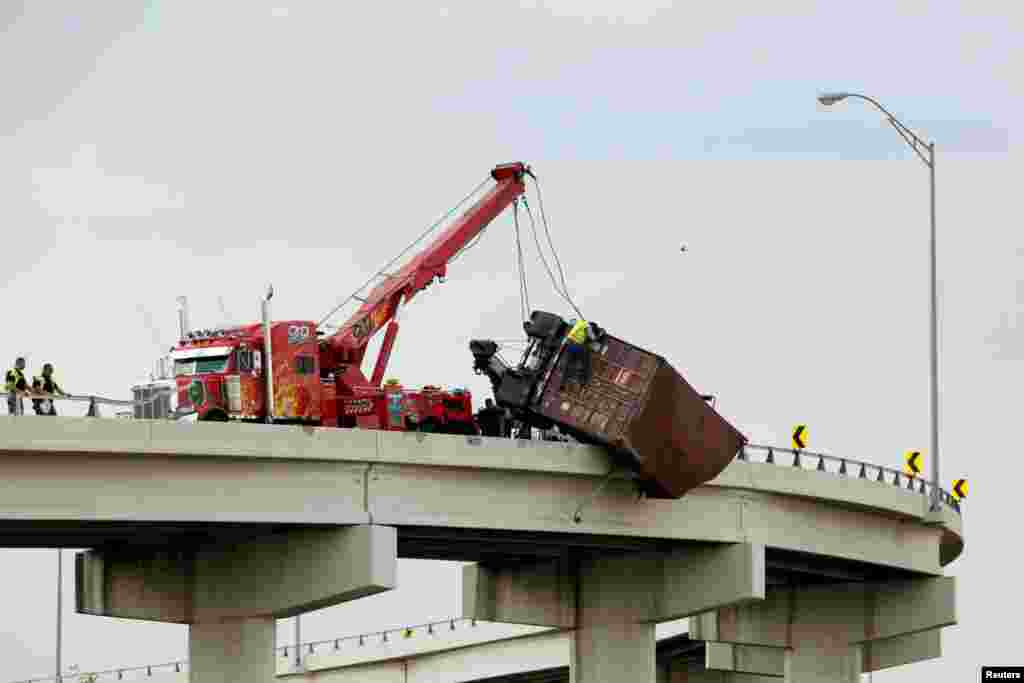 Workers assist as a trailer hangs from the U.S. 54 highway on the U.S side of Paso Texas, as seen from Ciudad Juarez, Mexico, July 3, 2017.