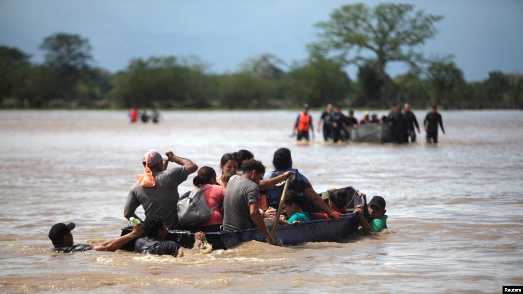 Flood-affected people cross a street on a boat in the aftermath of Hurricane Eta in La Lima, Honduras, Nov. 7, 2020.